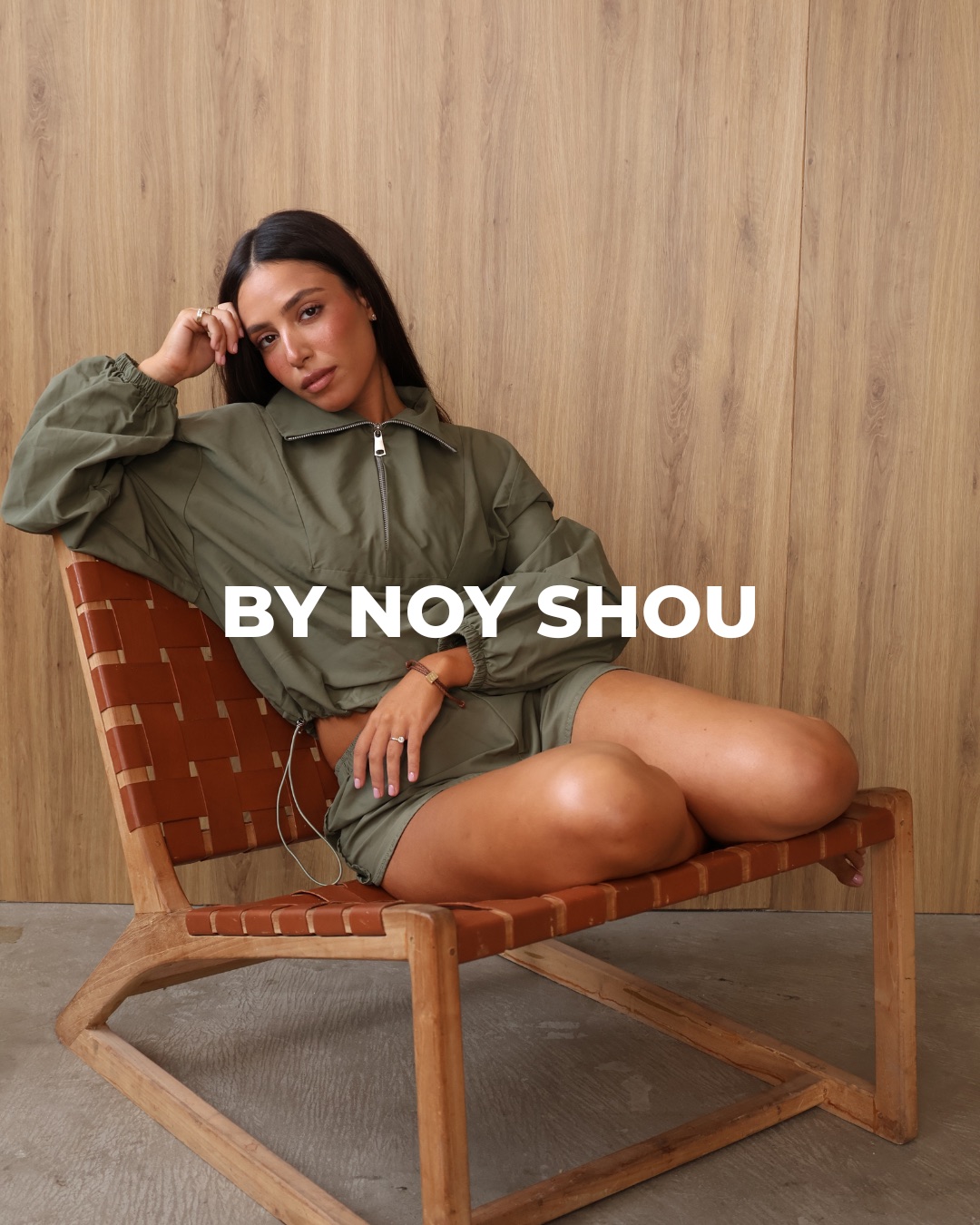 Noy in an olive half-zip set on a woven leather chair